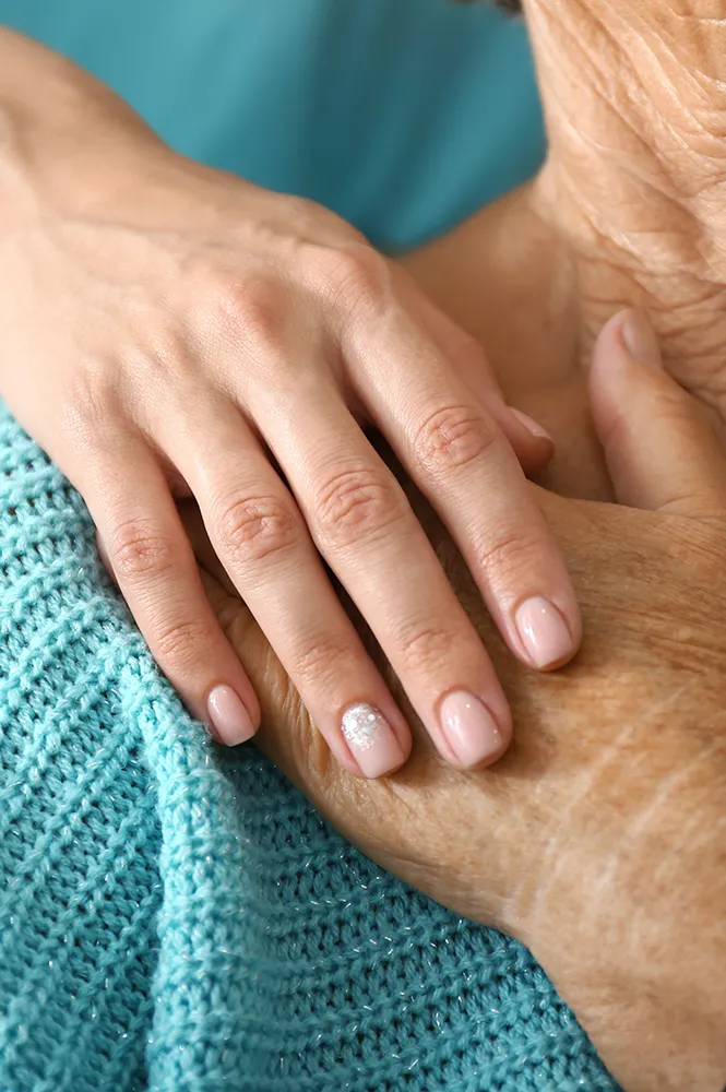 Hand einer Pflegerin hält die Hand einer Patientin